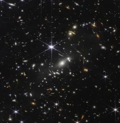Rappresentazione artistica di una galassia primordiale massiccia osservata dal telescopio spaziale James Webb