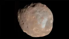 Rappresentazione artistica di una sonda spaziale in orbita attorno alla piccola e irregolare luna marziana Phobos, con il pianeta rosso sullo sfondo.
